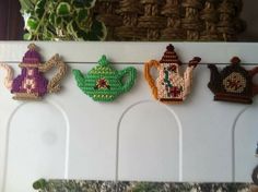 four cross stitch teapots are hanging on the wall