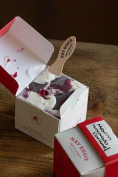 an open box with cake inside on a wooden table next to a spoon in it