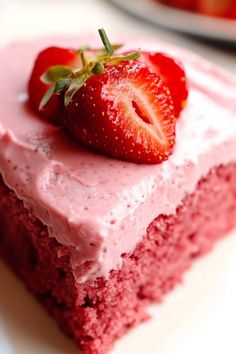 a piece of strawberry cake with frosting and a strawberry on top