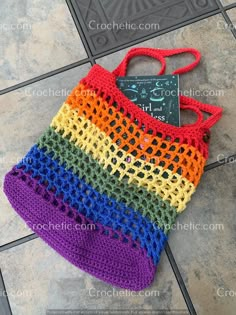 a multicolored crocheted bag sitting on the floor next to a book