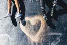 two people standing next to each other with their feet in the air and one has a heart drawn on the ground