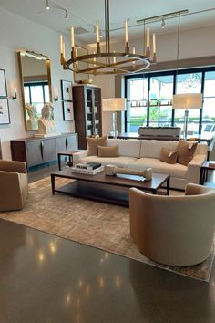 a living room filled with lots of furniture and large windows in the back drop off