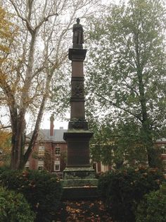 a statue in the middle of a park surrounded by trees