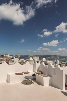 an outdoor seating area on the roof of a building with blue skies and clouds in the background