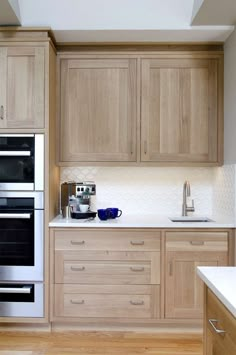 a kitchen with wooden cabinets and white counter tops, stainless steel appliances and wood flooring