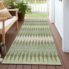 a green area rug sitting on top of a wooden floor next to a white door