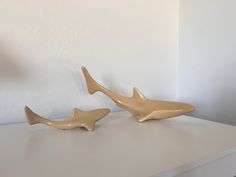 two ceramic sharks sitting on top of a white table next to a lamp and wall