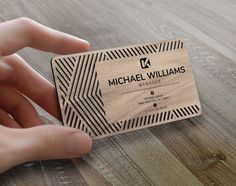 a hand holding a business card on top of a wooden table