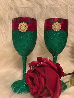 two wine glasses decorated with red and green glitter, one has a rose on it