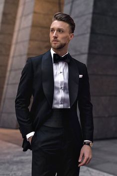 This modern black tie look is perfect for an urban wedding setting. The sharply tailored black tuxedo with satin lapels, white dress shirt, and black bow tie exude a contemporary and sophisticated vibe. The addition of a black waistcoat adds depth to the outfit, making it ideal for formal receptions and city weddings. Complete the look with polished black shoes and minimal accessories to maintain a clean, refined appearance.  Photo credit by: Imoue Masatako Tuxedo Suit For Men, Creative Black Tie, Wedding Suits Men Black, Black Suit Wedding, Urban Sophistication, Wedding Outfit Men, Groom Tuxedo, Suits Men