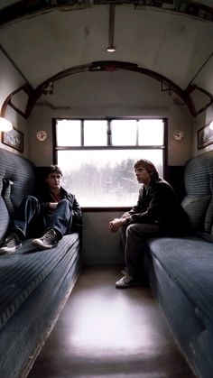 two people are sitting in a train car looking out the window