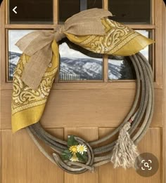 a wreath on the front door with a cowboy hat and lasso hanging from it