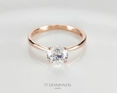 a rose gold ring with an oval cut diamond in the center, on a white background