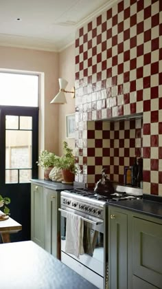 a kitchen with green cabinets and red checkered wall paper on the back splashing