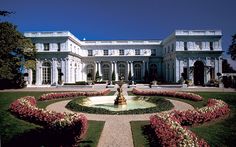 a large white house with a fountain in the middle of it's garden area