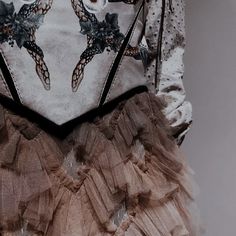 the back of a woman's dress with ruffled layers and an embroidered turtle on it