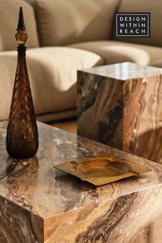 a marble table with a gold plate on it and a brown vase next to it