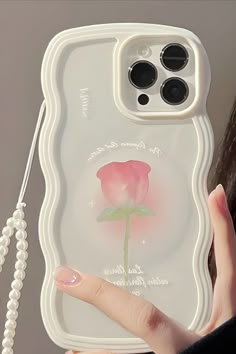 a woman holding up a phone case with a pink rose on it's side