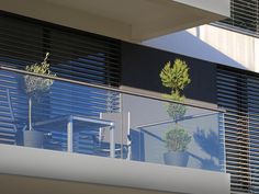 a balcony with two chairs and a plant on the balconies, overlooking an apartment building