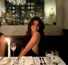 two women sitting at a table with candles in front of them and wine glasses on the table