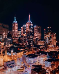 the city skyline is lit up at night with bright lights and skyscrapers in the background