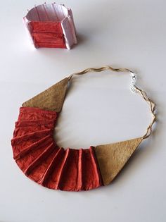 an origami necklace is shown next to a piece of paper that has been folded