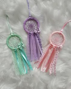 three small dream catchers are laying on a fluffy white surface