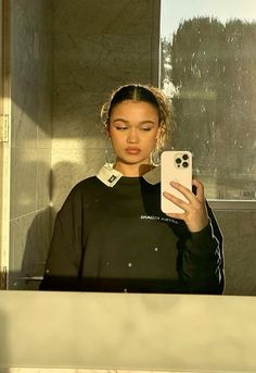 a woman taking a selfie in front of a mirror with her cell phone up to her ear