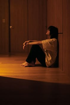 a woman sitting on the floor with her legs crossed looking up at something in the air