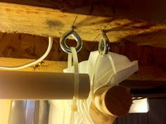 a pair of scissors hanging from the side of a piece of white fabric on a wooden beam