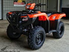 an orange four wheeler parked in front of a garage