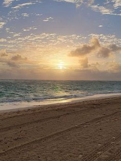 the sun is setting over the ocean on the beach