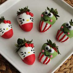 hello kitty strawberries are on a white plate with green and red decorations around them