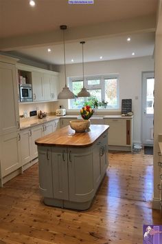 a large kitchen with an island in the middle and wooden flooring on the other side