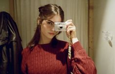 a woman taking a selfie in front of a mirror with a camera attached to her neck