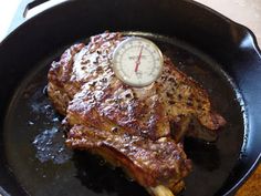 a piece of meat in a skillet with a thermometer