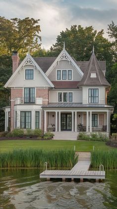 a large white house sitting on top of a lush green field next to a lake