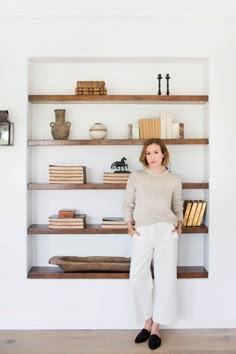 a woman standing in front of a book shelf with books on it and shelves behind her