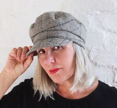 a woman with blonde hair wearing a gray hat and black shirt is looking at the camera