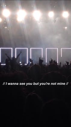 a group of people that are standing in front of a stage with lights on it