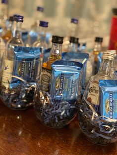 several bottles of alcohol are lined up on a wooden table with confetti in them