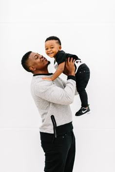 a man holding a small child up to his face while he holds it in the air