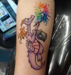 a colorful tattoo on the arm of a woman with a dragon holding a beer and sprinkles