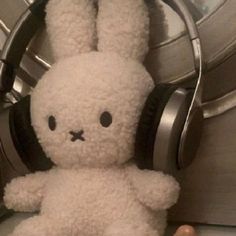 a white stuffed rabbit with headphones on sitting next to a pair of ear phones