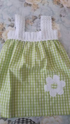 a green and white dress sitting on top of a bed next to a teddy bear