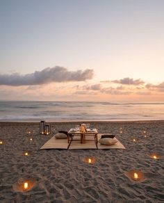 a table set up on the beach with candles