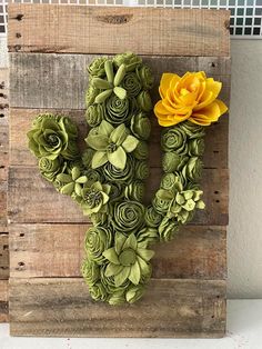 a cactus made out of paper flowers sitting on top of a wooden pallet wall