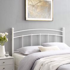 a white bed sitting in a bedroom next to a painting on the wall above it