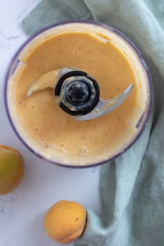 a blender filled with liquid next to two peaches