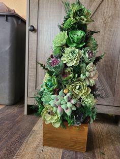 an artificial christmas tree made out of succulents and greenery in a wooden box